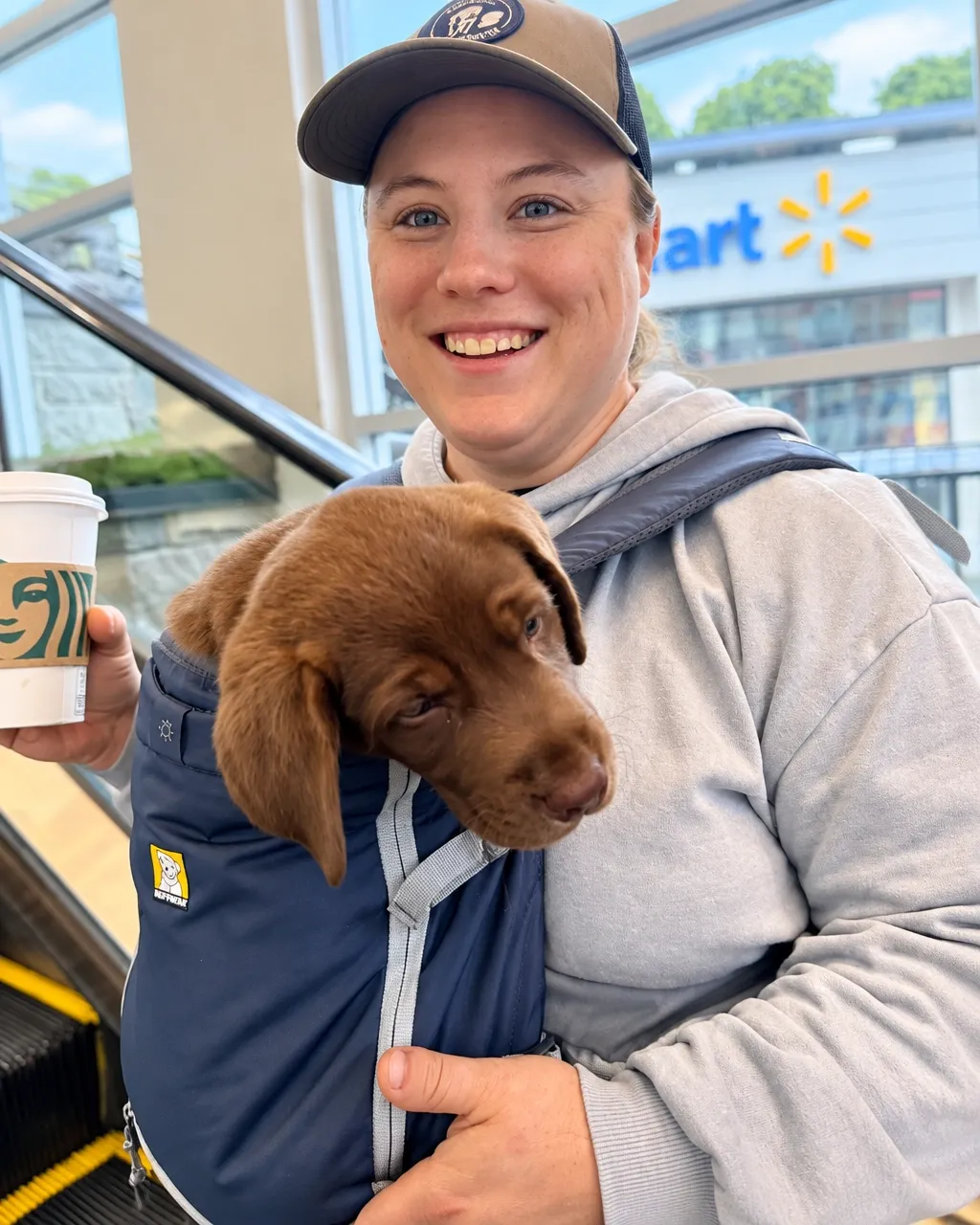Jenn, Pawsitively Service Dogs trainer, carrying a young puppy on a training outing